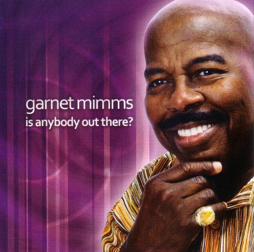 Garnet Mimms smiling with his hand on his chin against a purple background.
