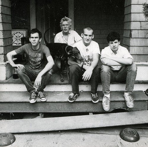 Black and white photo of four young men and a dog on a porch.