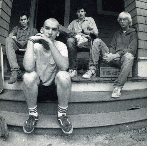 Black and white photo of four young men sitting on a porch.