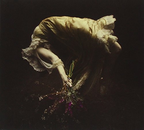 Person in flowing dress underwater holding a bouquet of flowers.
