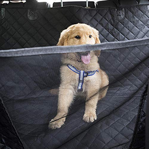 A golden retriever puppy sitting on a black quilted car seat cover.