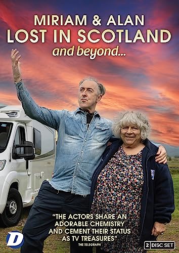 Miriam Margolyes and Alan Cumming stand in front of a campervan at sunset.