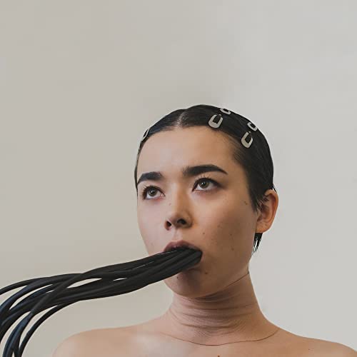 Close-up portrait of a woman with black cables extending from her mouth.