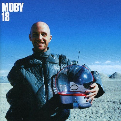 "Moby album cover: man holding astronaut helmet in a desert landscape."