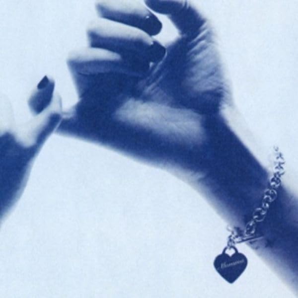 Two hands holding, with a bracelet and heart-shaped charm, in blue tones.