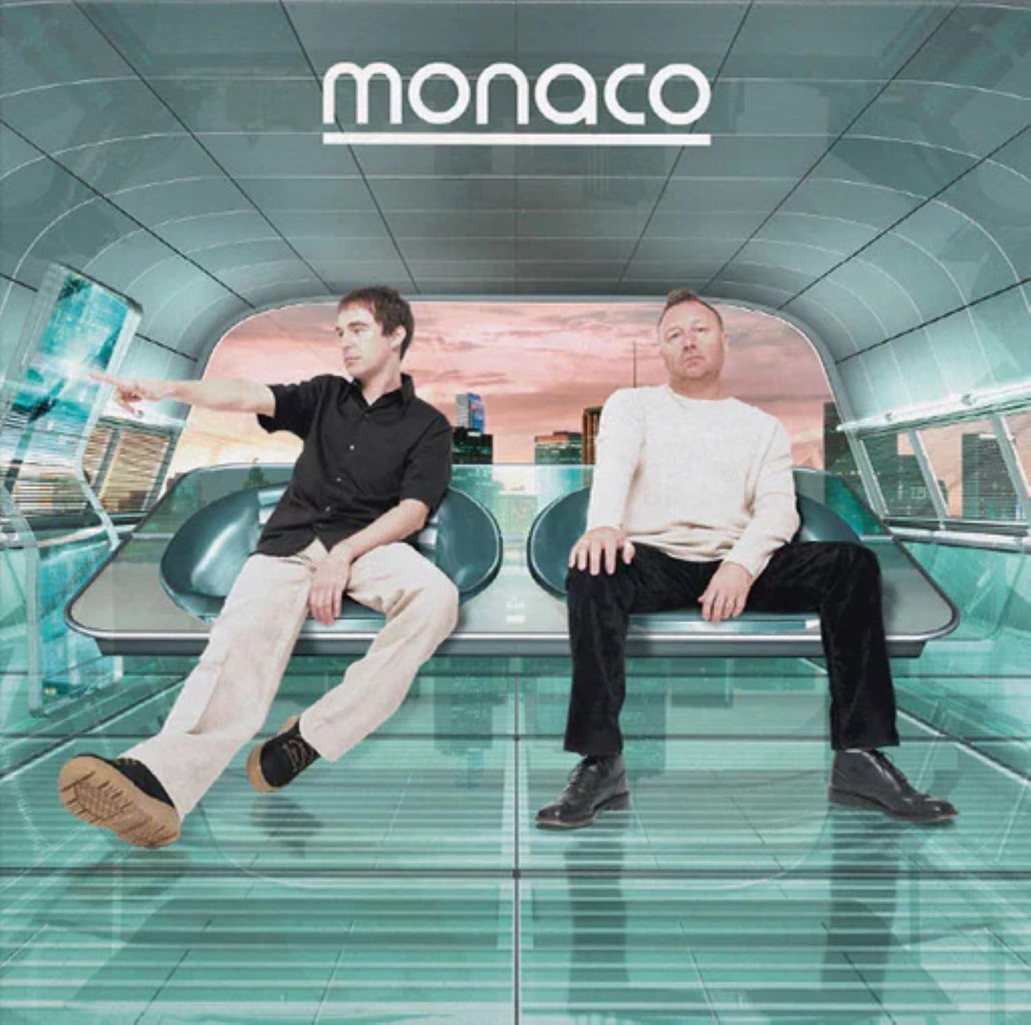 Two men sit on a futuristic bench overlooking a city skyline at sunset.