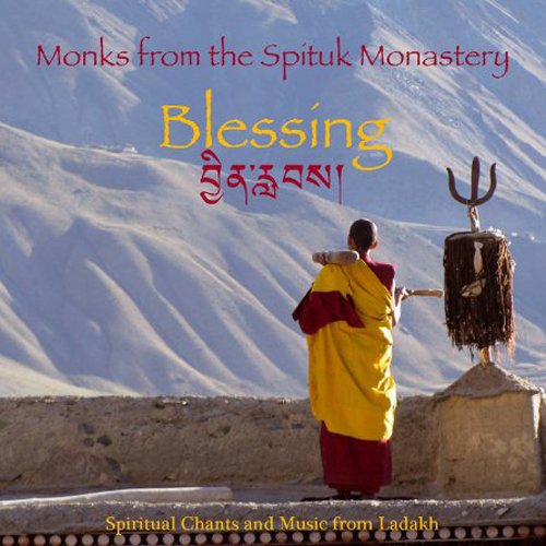 "CD cover featuring a monk in yellow robes standing before a trident on a mountain."
