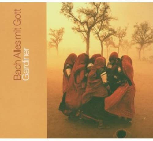 Group of people in red robes standing in a dusty landscape with bare trees.