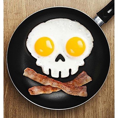 Skull-shaped fried eggs with bacon "bones" in a black frying pan.
