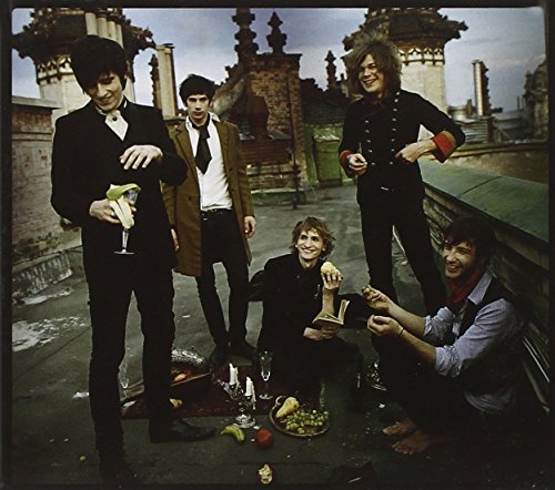 Five men in vintage clothing pose on a rooftop with fruit.
