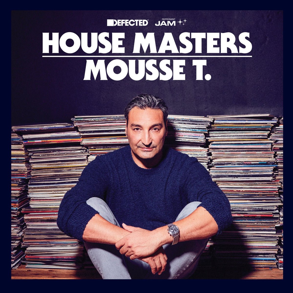 Mousse T. portrait in front of a large stack of vinyl records.