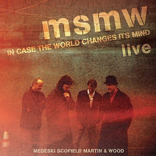Four men stand against a textured wall on the MSMW Live album cover.