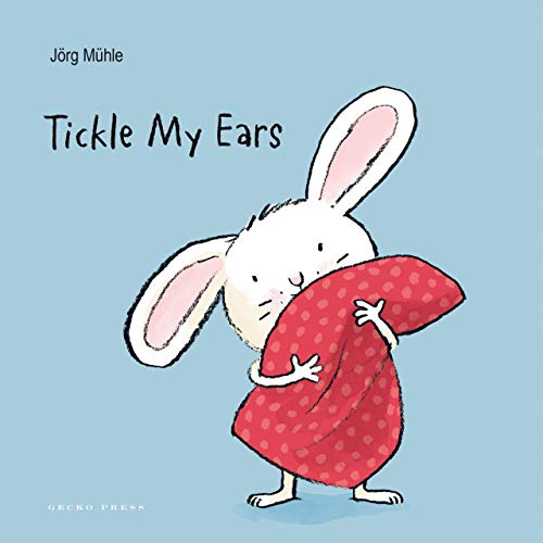 White rabbit with long ears hugging a red polka-dot blanket.