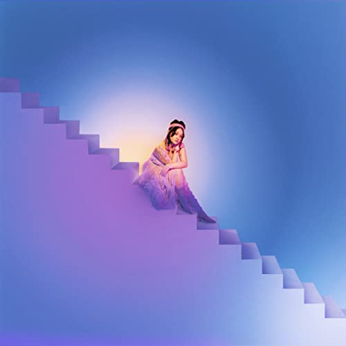 Woman sitting on blue stairs, album cover for Mxmtoon’s “Rising.”