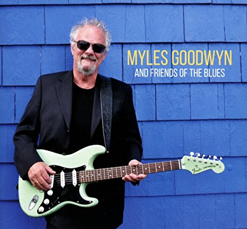 Myles Goodwyn holding a green electric guitar, blue shingled background.