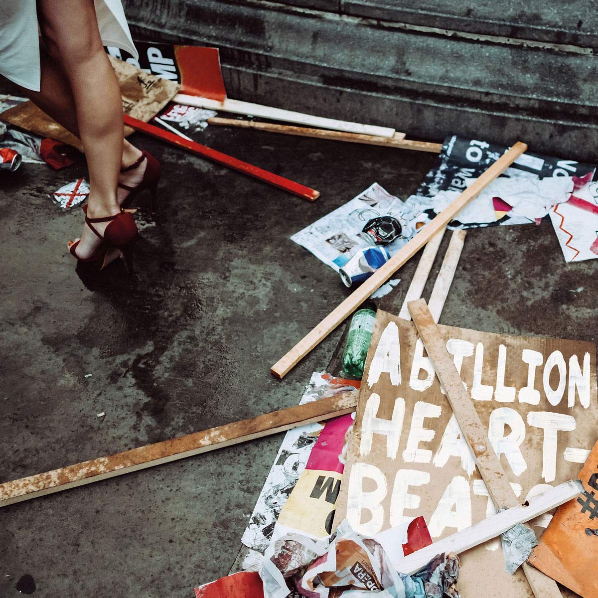 A pile of discarded protest signs, one reading "A BILLION HEARTBEATS", lies on the ground.