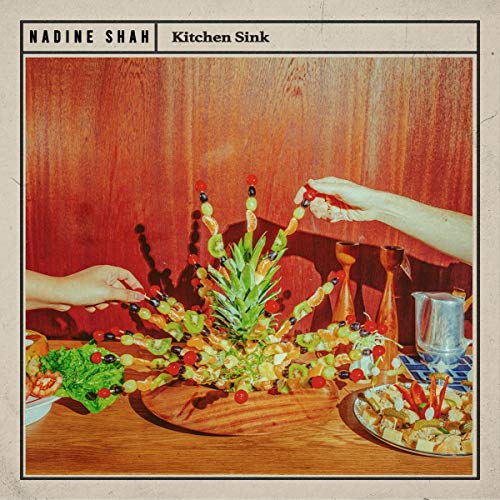"Album cover with a table of food, hands holding kebabs, and 'Nadine Shah Kitchen Sink' text."