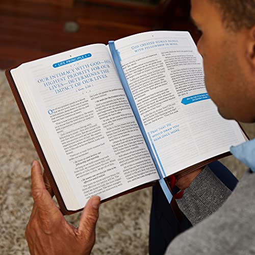 Open black leather Bible with text, held by a person’s hands.