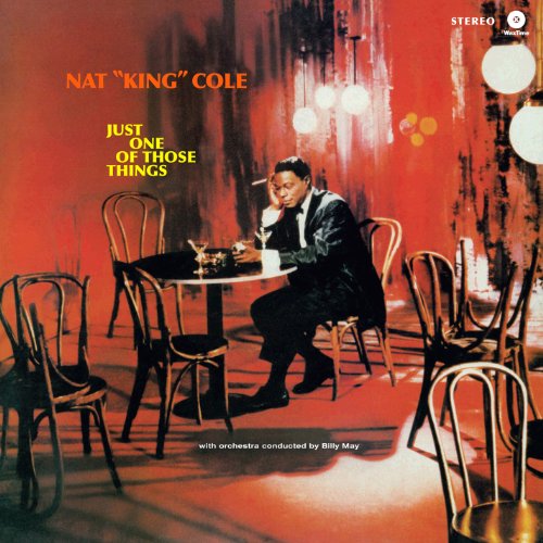 Nat King Cole sits at a table in a dimly lit, red-toned room.