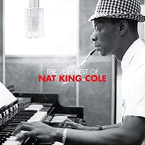 Black and white photo of Nat King Cole wearing a hat playing the piano.