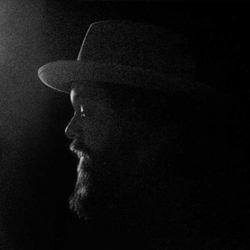 A low-key, grainy profile silhouette of a man wearing a fedora hat.