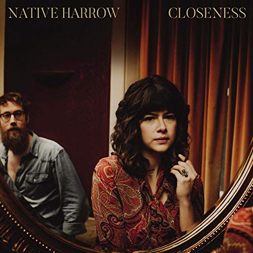 "Album cover: a woman looks in a mirror, man visible in reflection."
