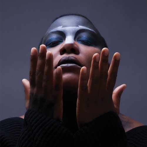 Meshell Ndegeocello portrait with dramatic blue and grey makeup, hands framing face.
