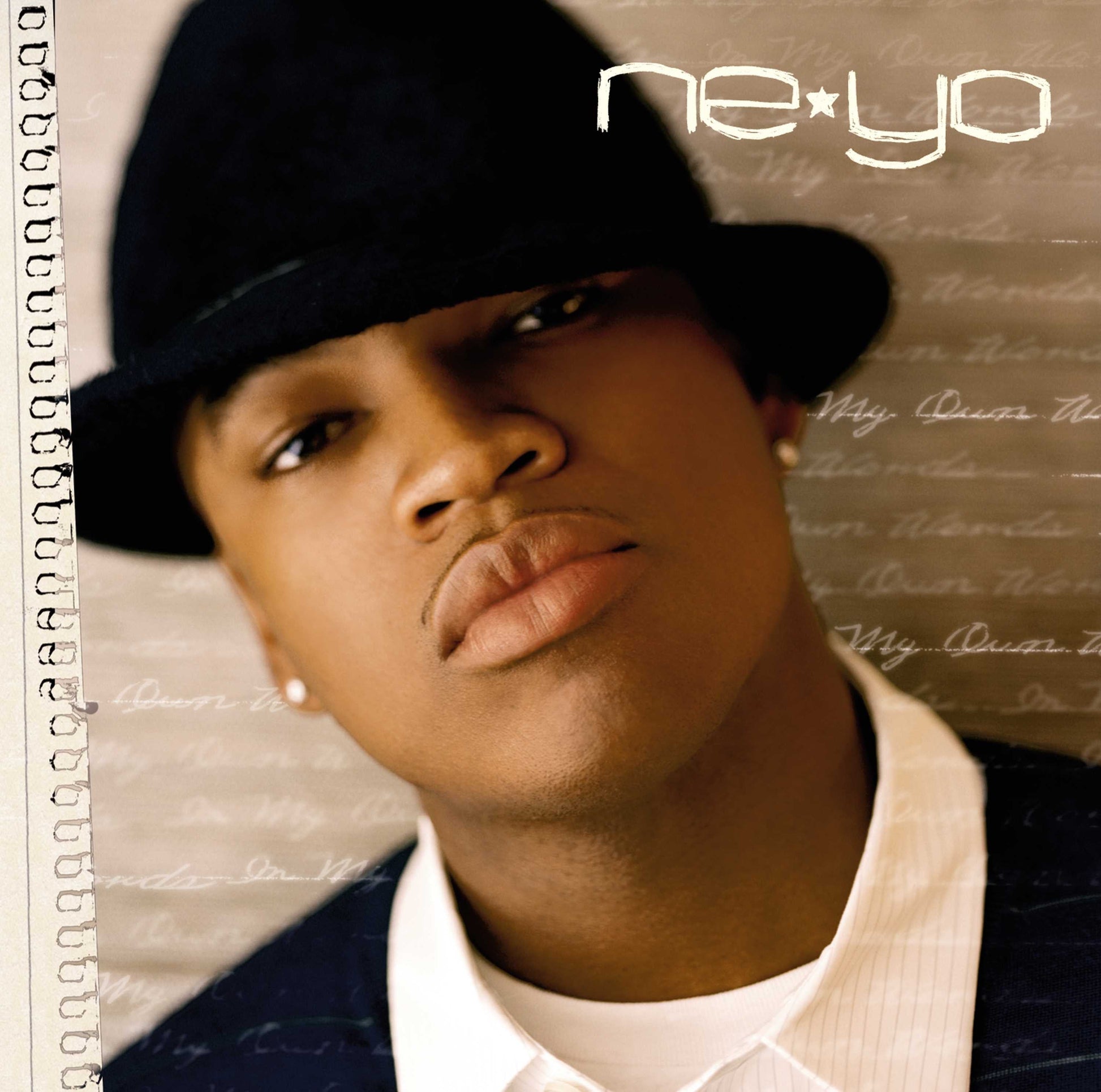 Ne-Yo wearing a black fedora against a background of handwritten script.
