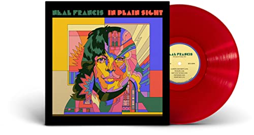 Red vinyl record next to album cover featuring a colorful stylized portrait.