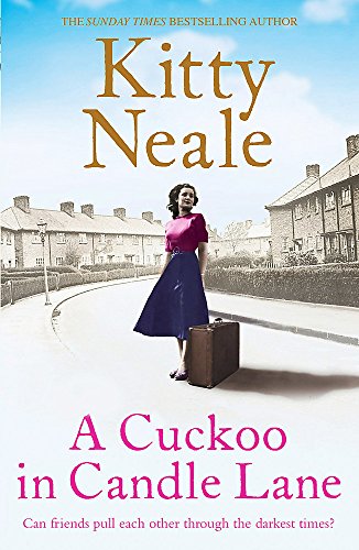 A woman with a suitcase stands on a street in front of terraced houses.