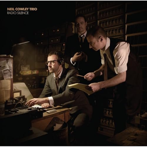 Album cover for Neil Cowley Trio’s “Radio Silence” featuring three men in suits.