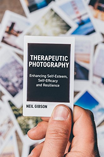 Hand holding a book titled "Therapeutic Photography" with black cover.