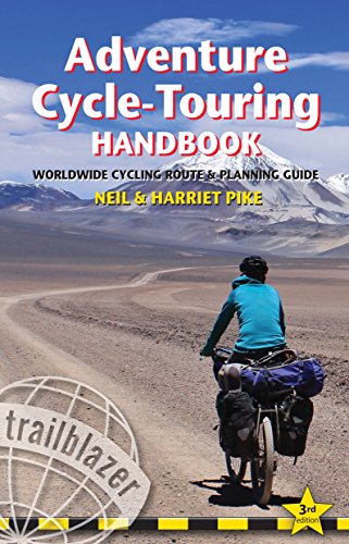 A cyclist rides a loaded touring bike along a remote mountain road.