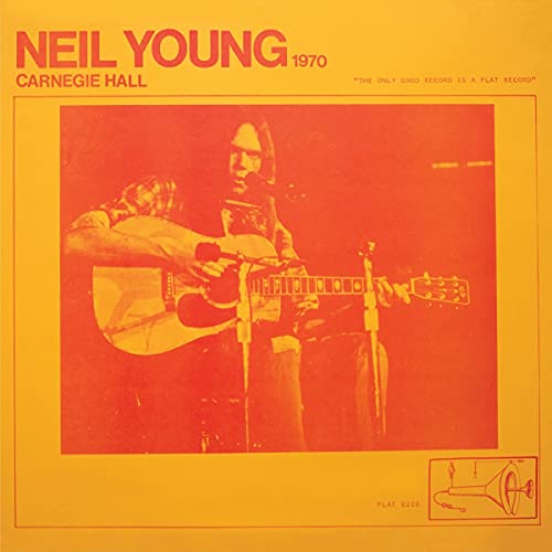 Neil Young playing acoustic guitar on stage, orange and red toned cover.