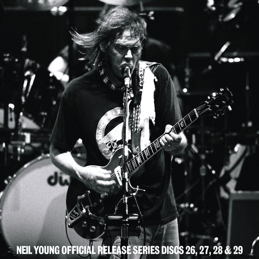 Black and white photo of Neil Young performing on stage with an electric guitar.