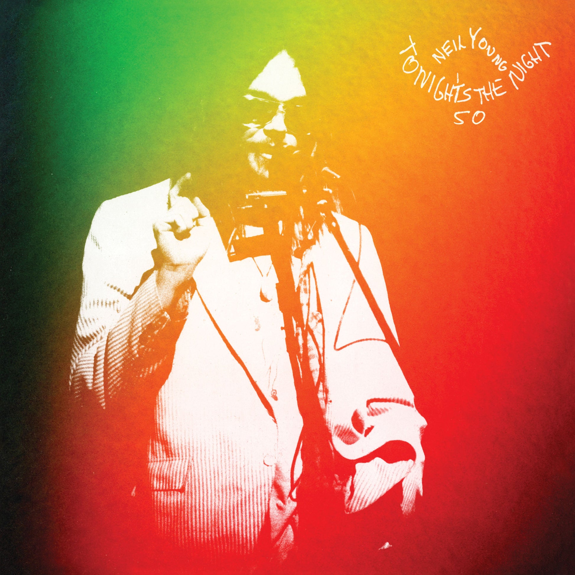 Neil Young performing on a gradient background of green, yellow, and red.