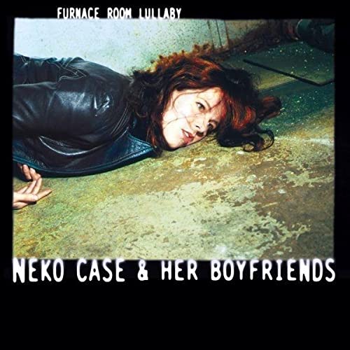 A woman with reddish hair in a leather jacket lies on a concrete floor.