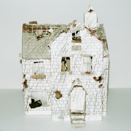 Damaged white brick dollhouse with missing sections, viewed straight on.