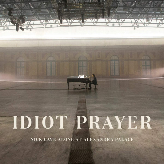 "CD cover featuring Nick Cave alone at a grand piano in a large, dimly lit hall."