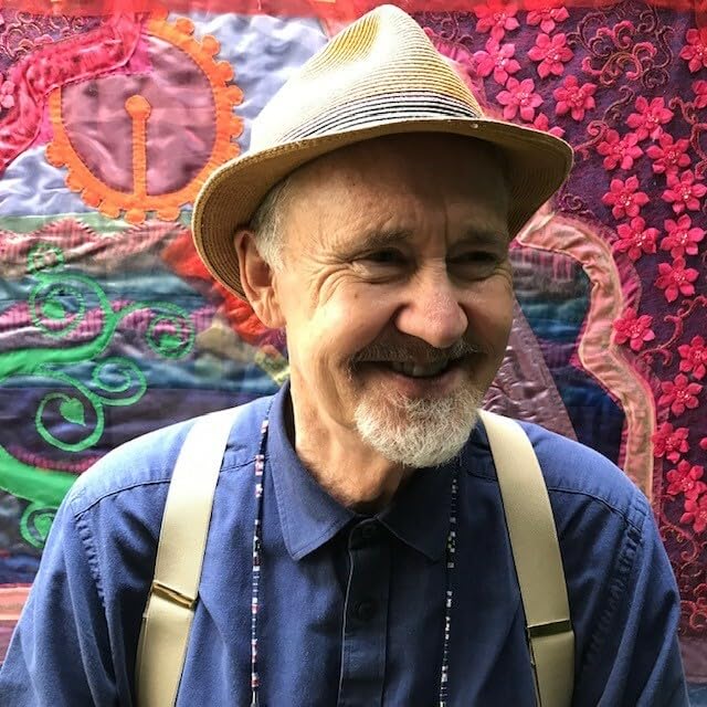 Smiling older man with a straw hat and suspenders, close-up portrait.