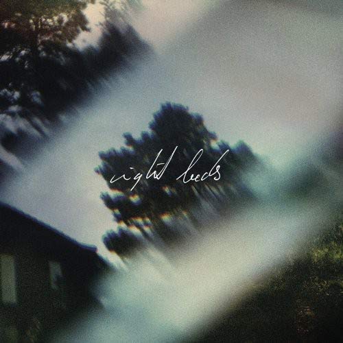 Blurry, atmospheric image of trees and a building with the text Night Beds.