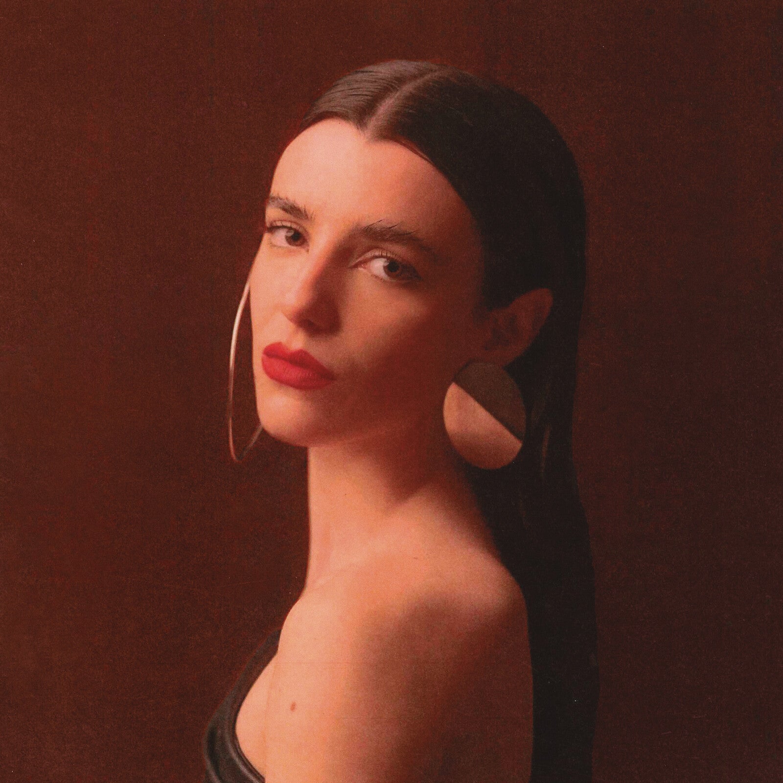 Portrait of Nina Maia with red lips and large silver earrings.