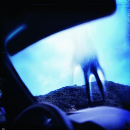 Blue and black album cover with a blurred figure and landscape.