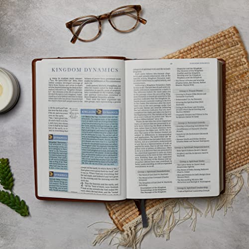 Open Bible showing Kingdom Dynamics study notes with glasses on a textured surface.