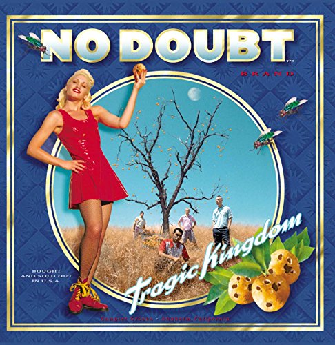 Gwen Stefani in a red dress stands before a tree with band members nearby.