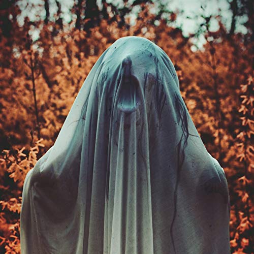 Figure draped in white cloth, facing away, with blurred orange background.