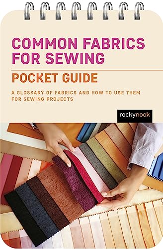 Spiral-bound sewing fabric guide with hands selecting colorful fabric swatches.