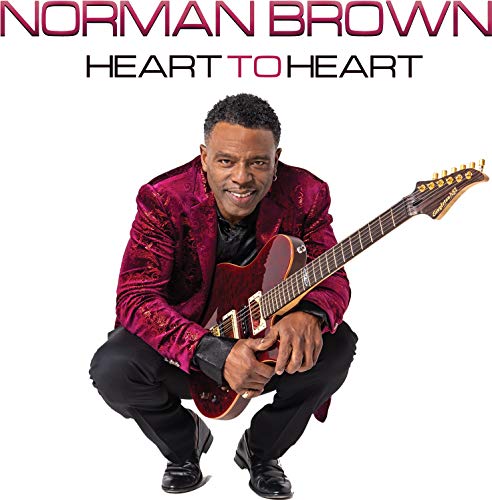 Norman Brown crouching and holding an electric guitar on a white background.