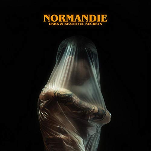A person with tattoos covered in plastic wrap against a black background, with "Normandie" text.