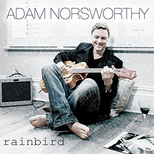 Album cover featuring a man sitting on the floor with an acoustic guitar.